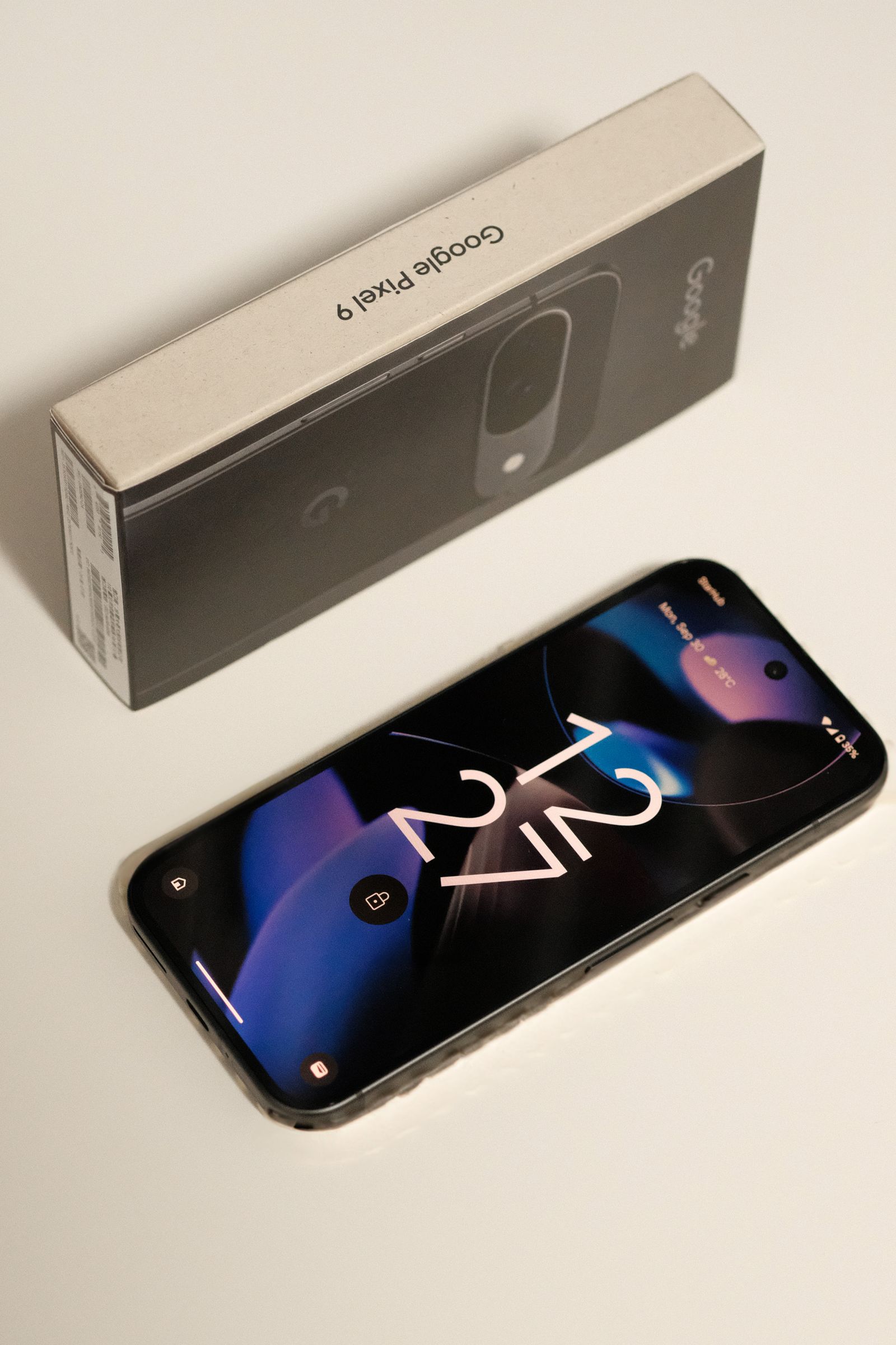 A real Google Pixel 9 smartphone beside its retail box